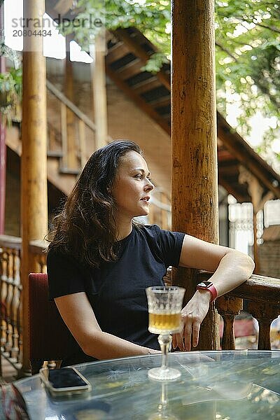 Tourist woman enjoys a chilled white wine in the rustic-style outdoor cafe  celebrating the simple pleasures of vacation