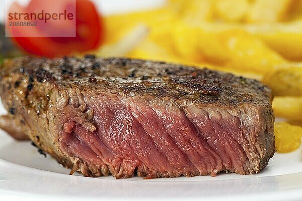 Closeup of a beef steak with french fries on a white background