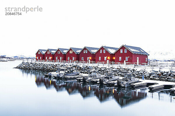 Row of red traditional wooden cabins standing above a small harbour in the snowy landscape  Leknes  Lofoten Islands  Norway  Scandinavia  Europe