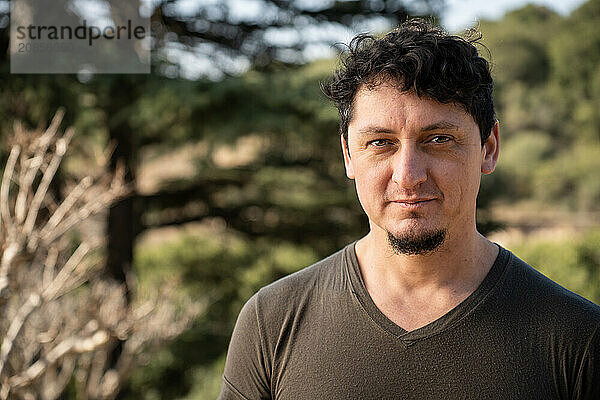 Close-up portrait of middle-aged caucasian man with a gaze and slight smile outdoors