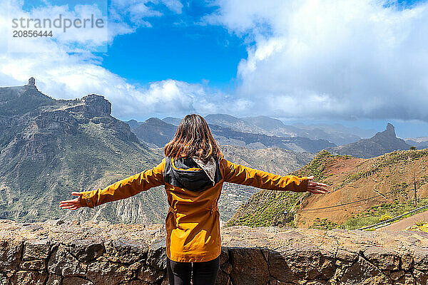 A tourist woman looking at Roque Nublo from a viewpoint with her arms open. Gran Canaria  Spain  Europe