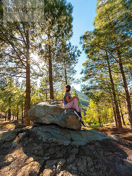 A woman sitting on a stone while hiking to Roque Nublo in Gran Canaria  Canary Islands