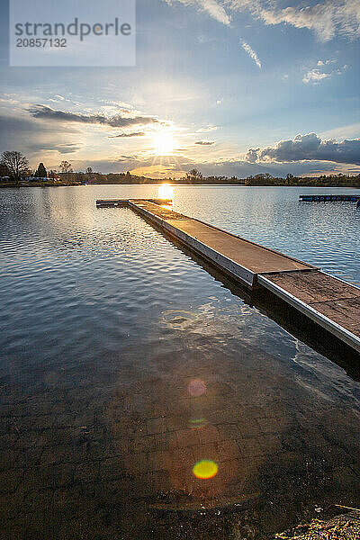 View from the shore into the distance and a sunset on the lake. The surroundings and the marvellous sky are reflected in the water. A great landscape shot Dutenhofener See  Hesse Germany