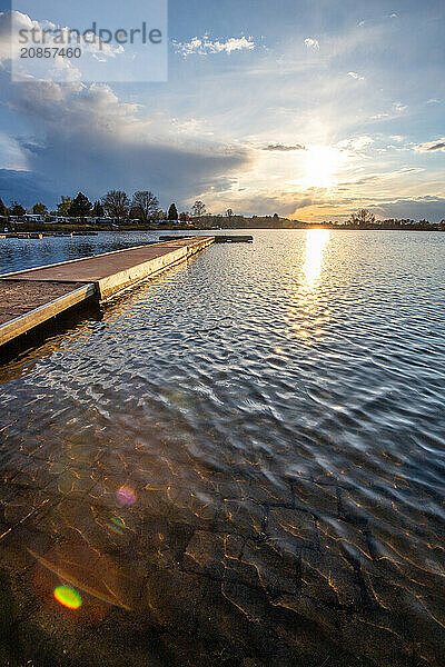 View from the shore into the distance and a sunset on the lake. The surroundings and the marvellous sky are reflected in the water. A great landscape shot Dutenhofener See  Hesse Germany