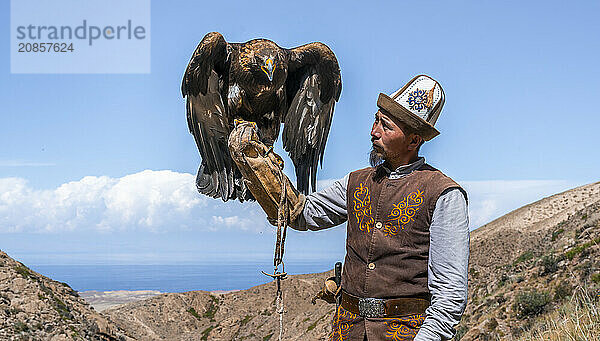 Traditional Kyrgyz eagle hunter with eagle in the mountains  hunting  eagle spreads its wings  near Bokonbayevo  Issyk Kul region  Kyrgyzstan  Asia