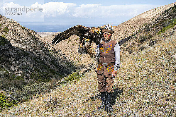 Traditional Kyrgyz eagle hunter with eagle in the mountains  hunting  near Bokonbayevo  Issyk Kul region  Kyrgyzstan  Asia