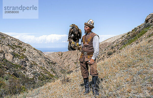 Traditional Kyrgyz eagle hunter with eagle in the mountains  hunting  near Bokonbayevo  Issyk Kul region  Kyrgyzstan  Asia