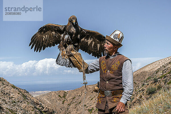 Traditional Kyrgyz eagle hunter with eagle in the mountains  hunting  eagle spreads its wings  near Bokonbayevo  Issyk Kul region  Kyrgyzstan  Asia