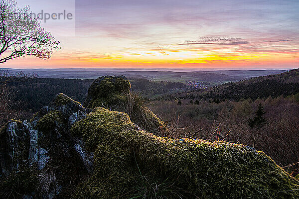 Panorama of a romantic landscape at sunset in the evening light. beautiful spring landscape in the mountains. Lawn and rolling hills. View from a cliff to the horizon. The Great Peak  Hesse  Germany  Europe