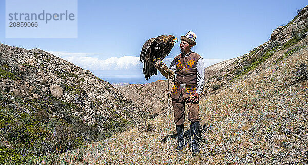 Traditional Kyrgyz eagle hunter with eagle in the mountains  hunting  near Bokonbayevo  Issyk Kul region  Kyrgyzstan  Asia