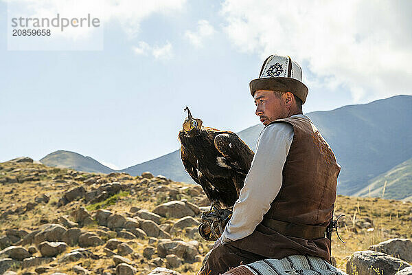 Traditional Kyrgyz eagle hunter riding with eagle in the mountains  hunting on horseback  near Bokonbayevo  Issyk Kul region  Kyrgyzstan  Asia