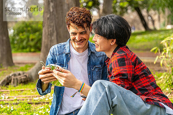 Gay couple enjoying a day in the park sitting together under the sun