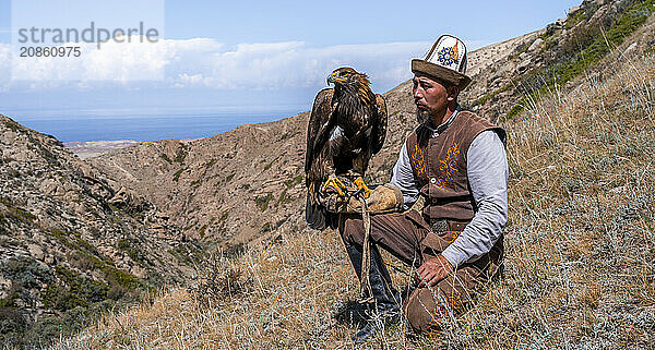 Traditional Kyrgyz eagle hunter with eagle in the mountains  hunting  near Bokonbayevo  Issyk Kul region  Kyrgyzstan  Asia