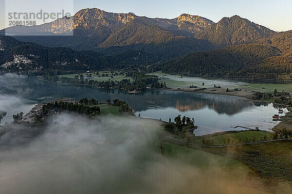 Aerial view of a mountain lake  mountains reflected in the lake  morning light  fog  summer  Lake Kochel  foothills of the Alps  Bavaria  Germany  Europe