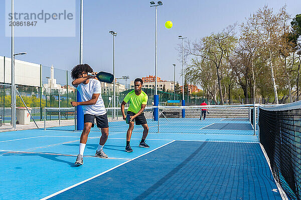 Full length photo with copy space of two african sportive friends playing pickleball together outdoors