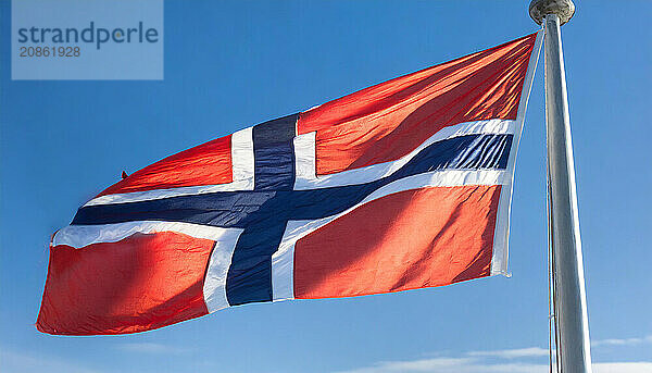 The flag of Norway flutters in the wind  isolated against a blue sky