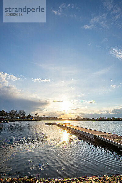 View from the shore into the distance and a sunset on the lake. The surroundings and the marvellous sky are reflected in the water. A great landscape shot Dutenhofener See  Hesse Germany