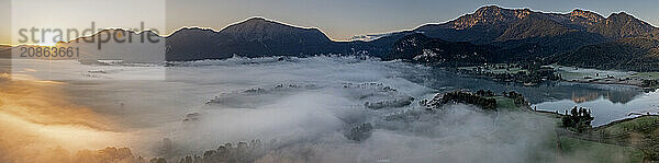 Aerial view  lake in fog in front of mountains  sunrise  backlight  panorama  summer  Lake Kochel and Kochler mountains  Alpine foothills  Bavaria  Germany  Europe