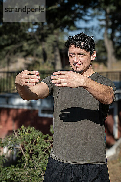 A middle-aged Caucasian man adopts the static posture of Tree Hugging  a crucial technique in Chi Kung practice