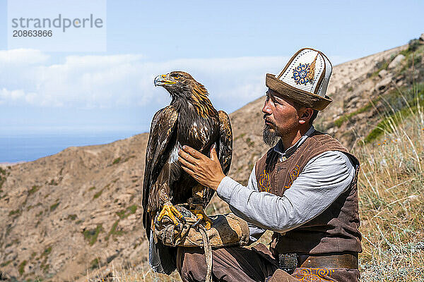 Traditional Kyrgyz eagle hunter with eagle in the mountains  hunting  near Bokonbayevo  Issyk Kul region  Kyrgyzstan  Asia