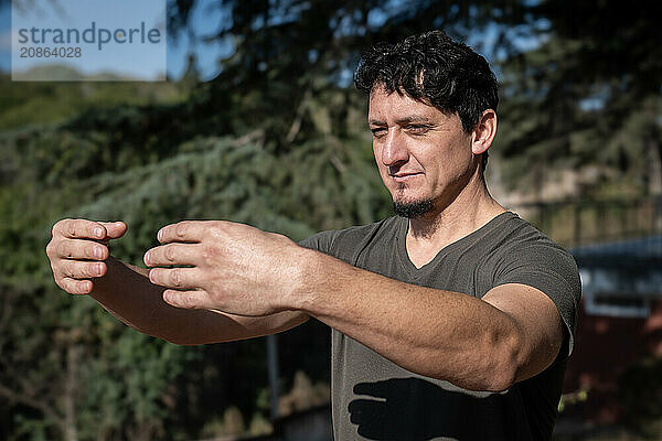 A Caucasian man adopts the Tree Hugging Posture during his Qi Gong training session. Rooted in ancient Chinese practices  this posture cultivates internal strength  balance  and energetic alignment