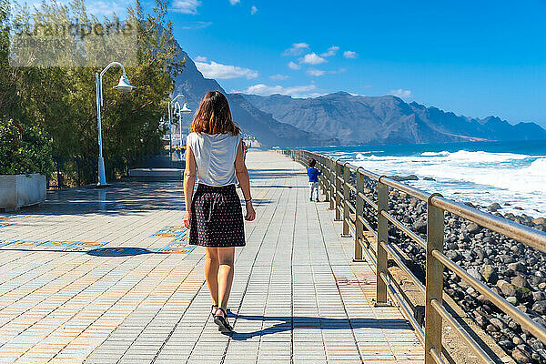 A woman strolling along the promenade in Agaete in Puerto de Las Nieves in Gran Canaria  Spain  Europe