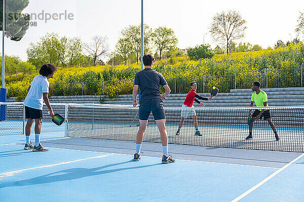 Friends playing pickleball in an outdoor court in a sunny day