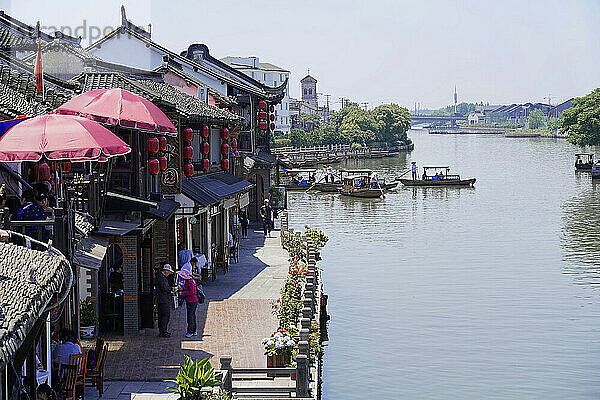 Excursion to Zhujiajiao water village  Shanghai  China  Asia  wooden boat on canal with view of historical architecture  people walking along a promenade with traditional Chinese architecture  Asia