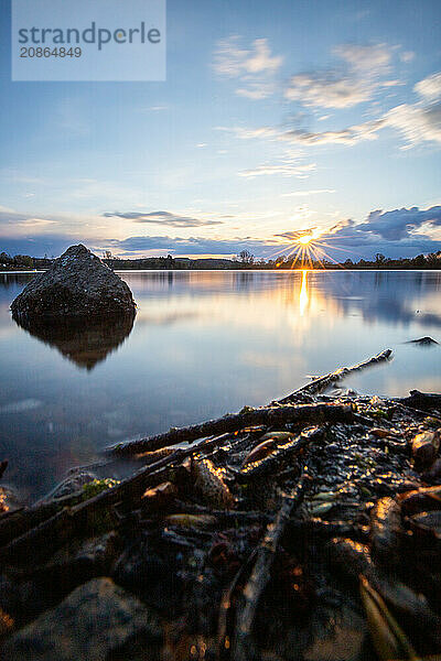 View from the shore into the distance and a sunset on the lake. The surroundings and the marvellous sky are reflected in the water. A great landscape shot Dutenhofener See  Hesse Germany