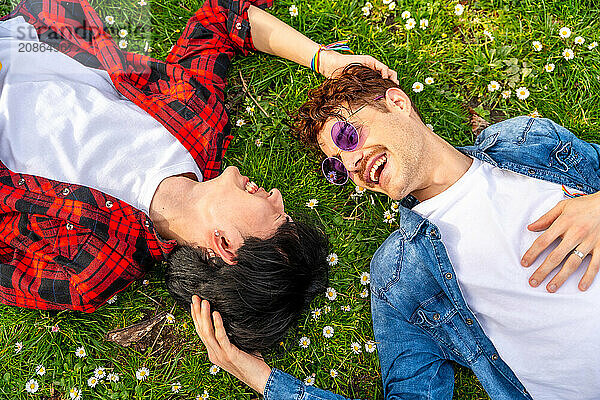 Top view of a multiracial gay couple enjoying spring lying on a park together