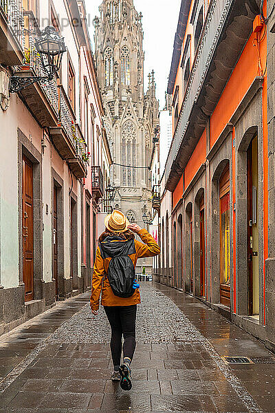 A tourist woman with a hat walking along a beautiful street next to the Church of San Juan Bautista  Arucas Cathedral  Gran Canaria  Spain  Europe