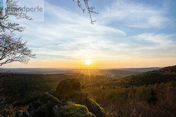 Panorama of a romantic landscape at sunset in the evening light. beautiful spring landscape in the mountains. Lawn and rolling hills. View from a cliff to the horizon. The Great Peak  Hesse  Germany  Europe