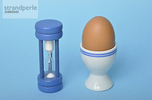 Boiled egg and hourglass on a blue background