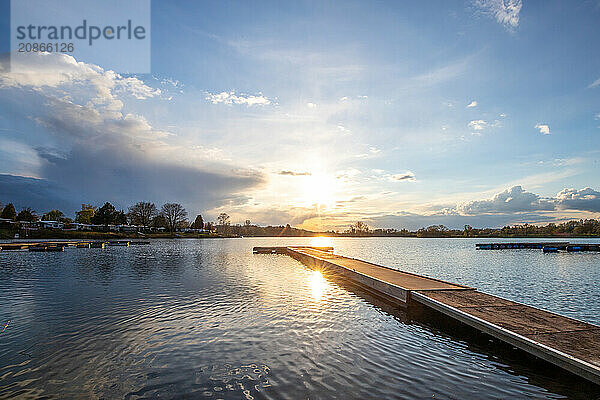 View from the shore into the distance and a sunset on the lake. The surroundings and the marvellous sky are reflected in the water. A great landscape shot Dutenhofener See  Hesse Germany