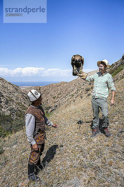 Traditional Kyrgyz eagle hunter  tourist holding eagle in his arms  near Bokonbayevo  Issyk Kul region  Kyrgyzstan  Asia