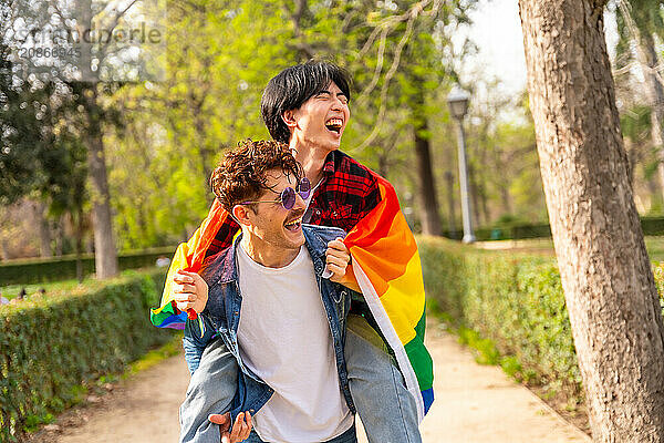 Romantic and happy scene of a multiracial happy gay couple piggybacking and laughing in a park