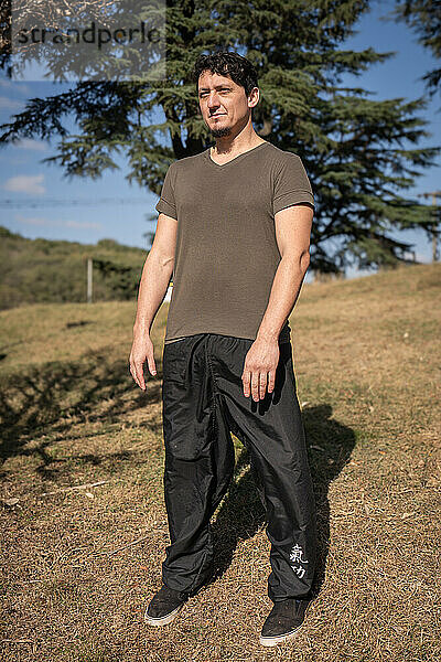 A man outdoors adopts the Wu Chi posture  known as The Void  which marks the beginning of his qi gong or chi kung training session