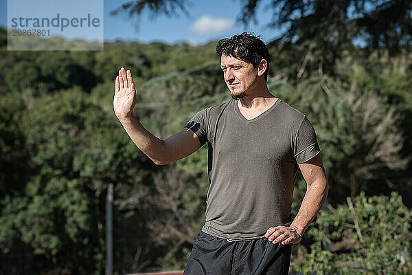 Portrait of a man practicing the third posture of the Bai Hu program  the static stance Santi Shi  focusing on pushing strength  outdoors