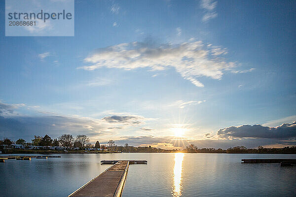 View from the shore into the distance and a sunset on the lake. The surroundings and the marvellous sky are reflected in the water. A great landscape shot Dutenhofener See  Hesse Germany