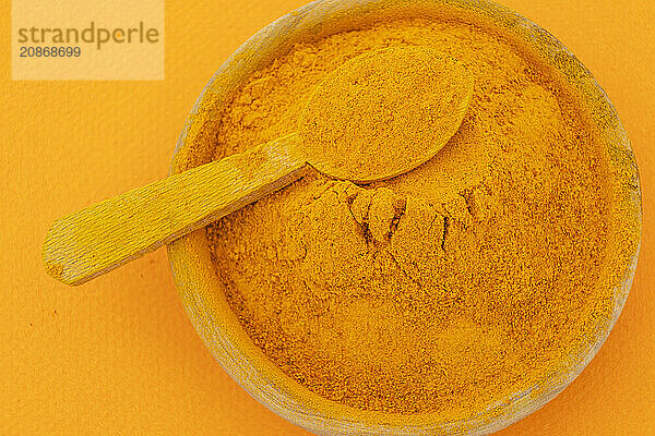 Ground turmeric on orange background