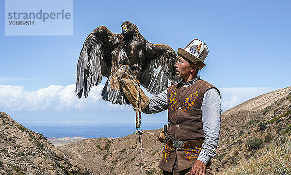 Traditional Kyrgyz eagle hunter with eagle in the mountains  hunting  eagle spreads its wings  near Bokonbayevo  Issyk Kul region  Kyrgyzstan  Asia