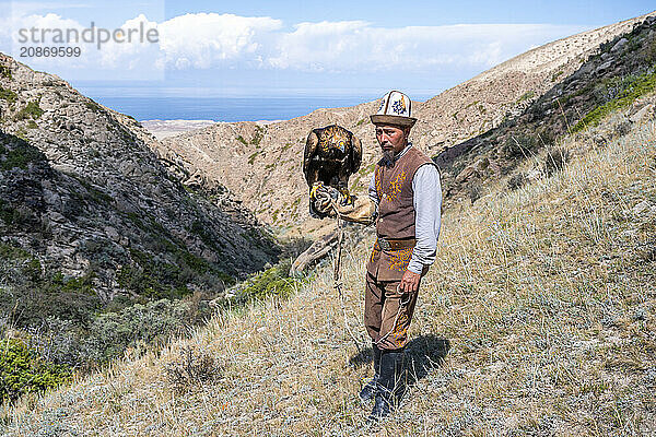 Traditional Kyrgyz eagle hunter with eagle in the mountains  hunting  near Bokonbayevo  Issyk Kul region  Kyrgyzstan  Asia