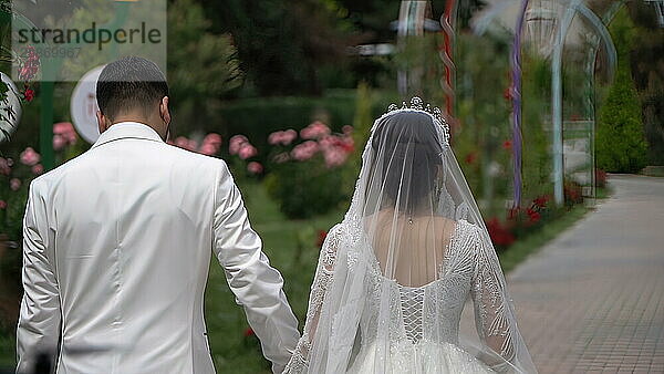 The bride and groom are walking in the park on their wedding day