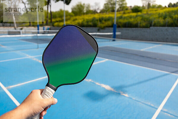 Close-up of a hand holding pickleball racket in an outdoor court