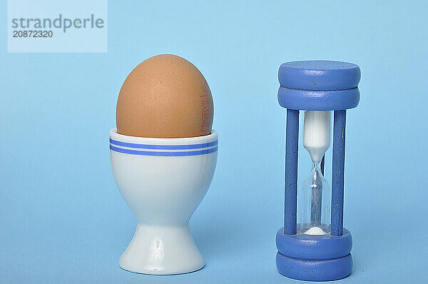 Boiled egg and hourglass on a blue background