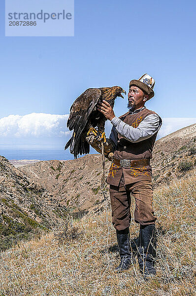 Traditional Kyrgyz eagle hunter with eagle in the mountains  hunting  near Bokonbayevo  Issyk Kul region  Kyrgyzstan  Asia