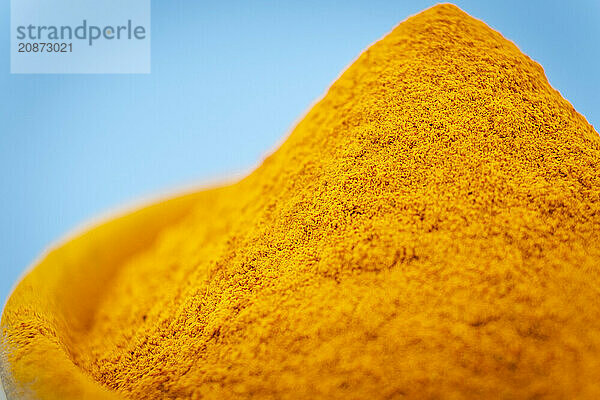 Ground turmeric on blue background