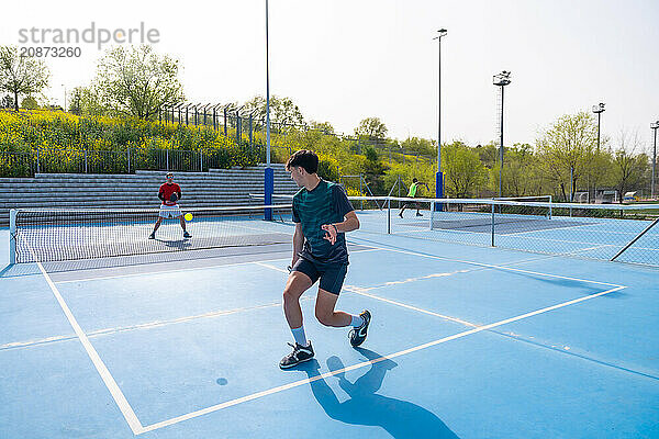 Sportive young friends working out playing pickleball in an outdoor facility