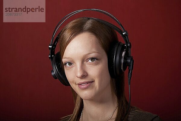 Girl with headphones on a red background