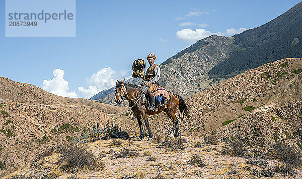 Traditional Kyrgyz eagle hunter riding with eagle in the mountains  hunting on horseback  near Bokonbayevo  Issyk Kul region  Kyrgyzstan  Asia